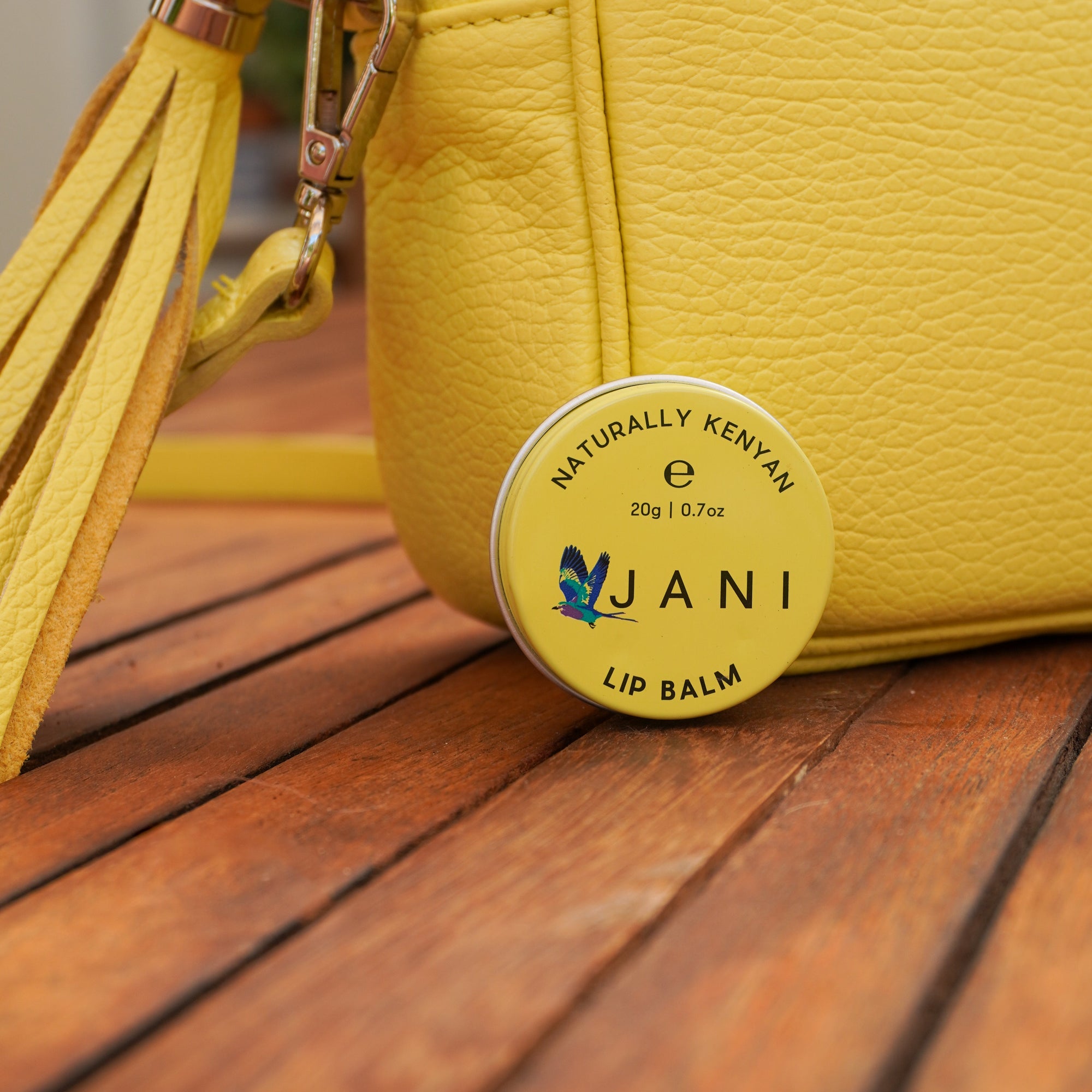 Yellow lip balm container with tassel on a wooden surface