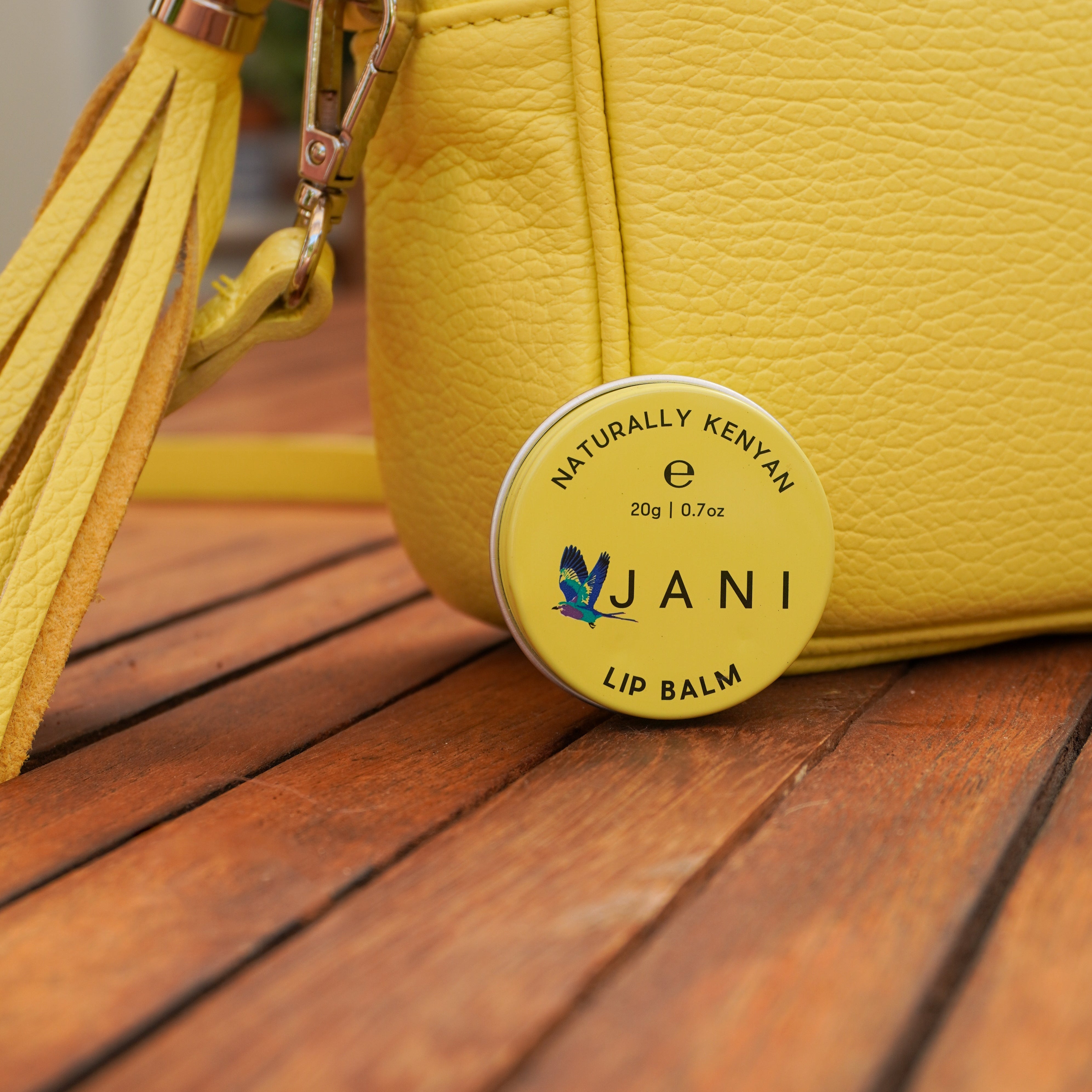 Yellow lip balm container with tassel on a wooden surface
