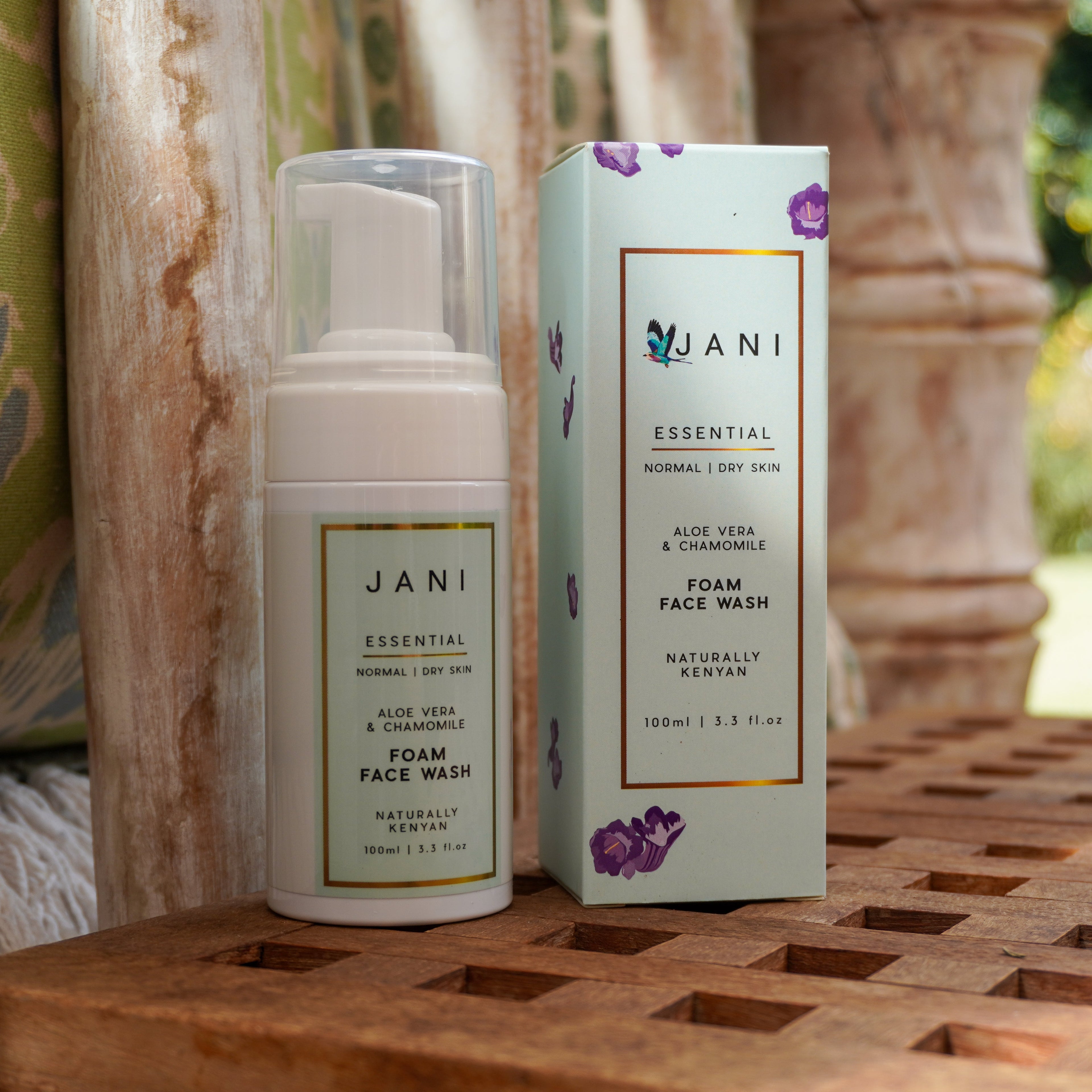 JANI essential foam face wash bottle and packaging on a wooden surface with a blurred natural background