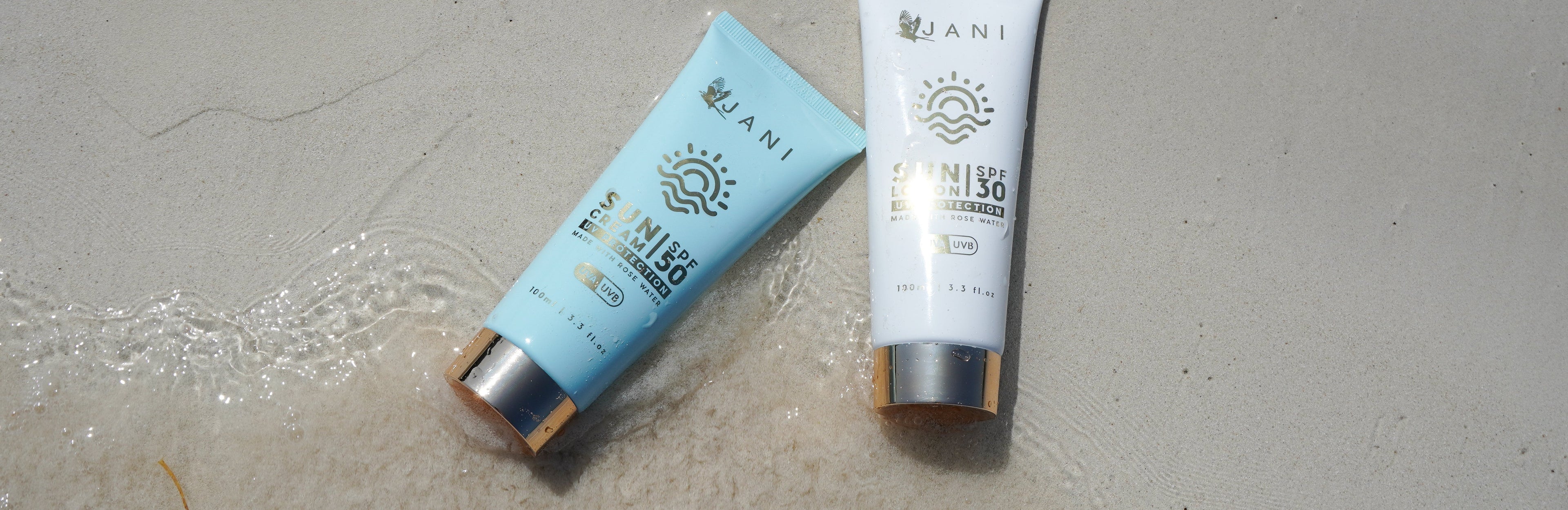 Two sunscreen tubes from the brand 'JANI' on a the beach
